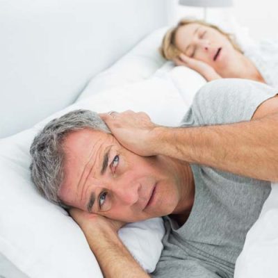 A man having trouble sleeping while his partner is snoring due to her sleep apnea
